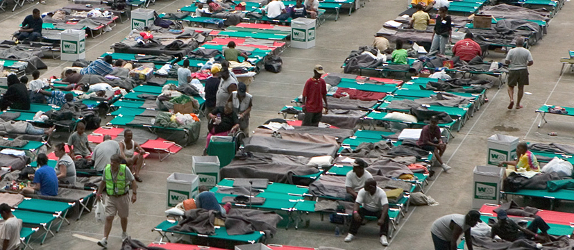 An emergency shelter during hurricane Katrina, with people sitting around on cots