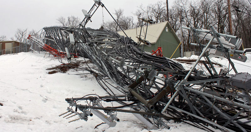 Collapsed cell phone tower on ground, in the snow