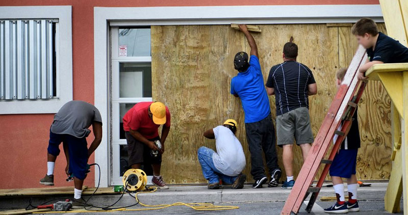 Men installing plywood over glass doors in preparation for hurricane arrival