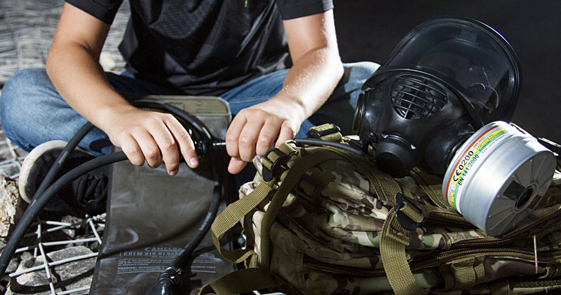 Mira Safety CM-6M Gas Mask water bladder integration: man attaching tubes from a backpack