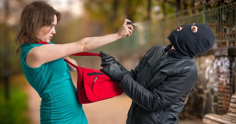 Woman pepper spraying a purse thief in a mask