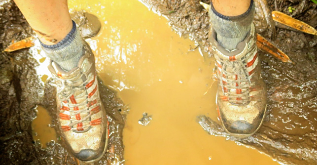 Darn Tough Vermont Merino Wool Socks in action, on a woman's feet who is standing in the mud over a puddle