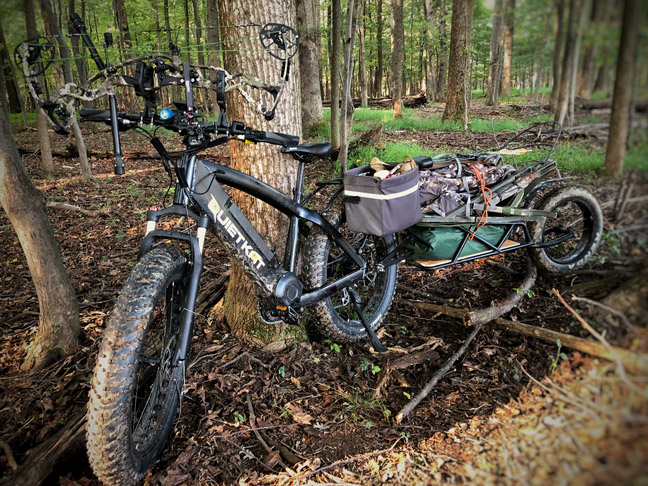 QuietKat All Terrain Electric Bike leaning against a tree with a trailer