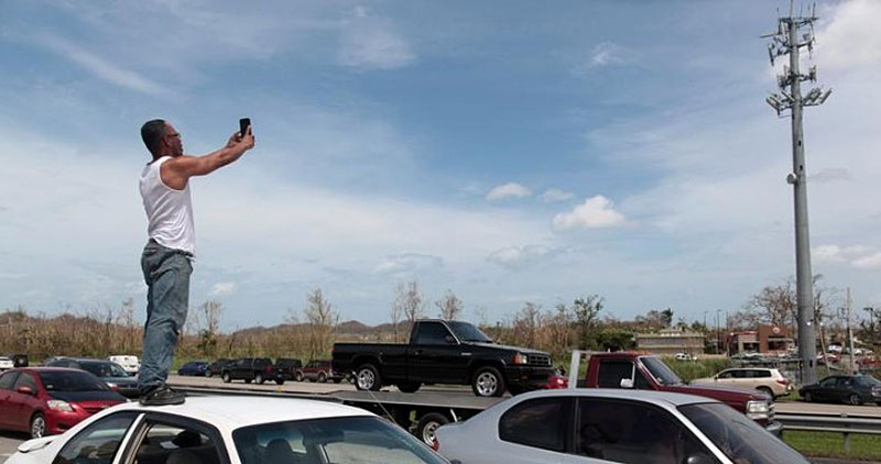 Guy on a car trying to get a cell signal from a tower in front of him
