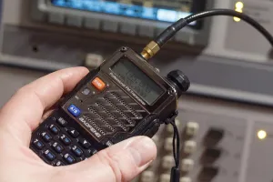 A Baofeng UV-5R connected to another antenna in front of electrical equipment
