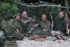 Participants in a survival school sitting around a bushcraft hut