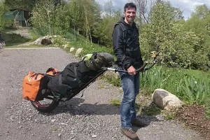 A man with a rolling backpack cart