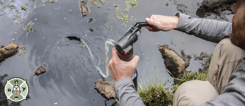 Man using a water purifier on a river bank
