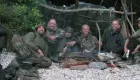 Participants in a survival school sitting around a bushcraft hut